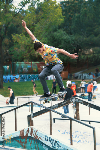 Plakat młody skateboarder trenuje na skate parku w poręczy / miejski skater robi sztuczki na rampie i railling in skatepark