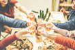 © Alessandro Biascioli - Group of friends enjoying dinner toasting with beers and eating pizza at home