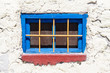 small blue window with yellow grating. bright colors in the background of white wall Santorini Greece