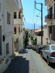Naklejka na meble Narrow street of Agios Nikolaos city. Crete, Greece. Hot season, July.