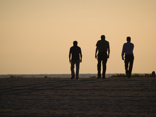 three men walking on beach