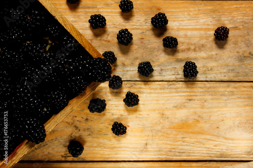 Fotografija Ripe blackberries in a basket on a rustic wooden table.