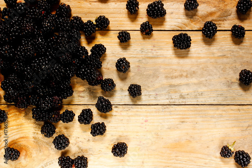 Fotografia, Obraz Ripe blackberries in a basket on a rustic wooden table.
