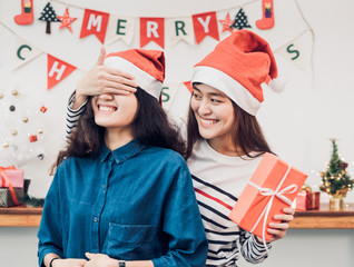 Asia girl lovers couple,girlfriend close eye to surprise friend by giving Christmas present  at house party,Holiday celebrating season,Lovely lesbian couple