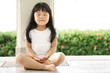 © kornnphoto - Asian children cute or kid girl sit for meditation with peace and relax in garden pavilion at temple or church and wearing white dress with sunlight on white with space