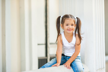 happy little girl sitting on the staircase railing and smiling