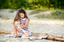 Beautiful Little Girl On The Beach Playing With Sand And Having Fun.