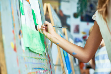 Wall Mural - Mid section portrait of unrecognizable schoolgirl painting in art studio, closeup hand painting on easel