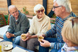 © Seventyfour - Group of cheerful seniors enjoying time together drinking tea in outdoor cafe and sharing life stories in retirement