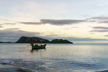 Wall Mural - beautiful panorama landscape of silhouette fisherman boat floating in sea at the beach at dusk and reflection on sea. boat in the sea in evening when sunset with golden light with mountain background