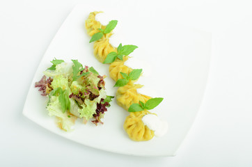 Dumplings with sour cream and greens decorated basil on a plate isolated on white background