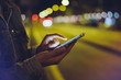 © A_B_C - Girl pointing finger on screen smartphone on background illumination glow bokeh light in night atmospheric city, hipster using in hands mobile phone, mockup glitter street online internet concept