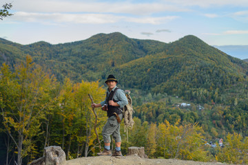 senior traveler man climbed to the top of the mountain. an old man is a tourist with a backpack and 
