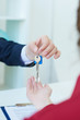 © cameravit - Broker giving keys of new house. In background is a contract visible.