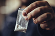 © DedMityay - Man hand holds plastic packet or bag with cocaine or another drugs, drug abuse and danger addiction concept