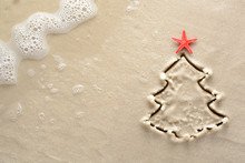 Holiday Background - Christmas Tree With Starfish Drawn On A Sandy Beach