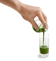 Wall Mural - Woman pouring wheat grass drink into shot on white background