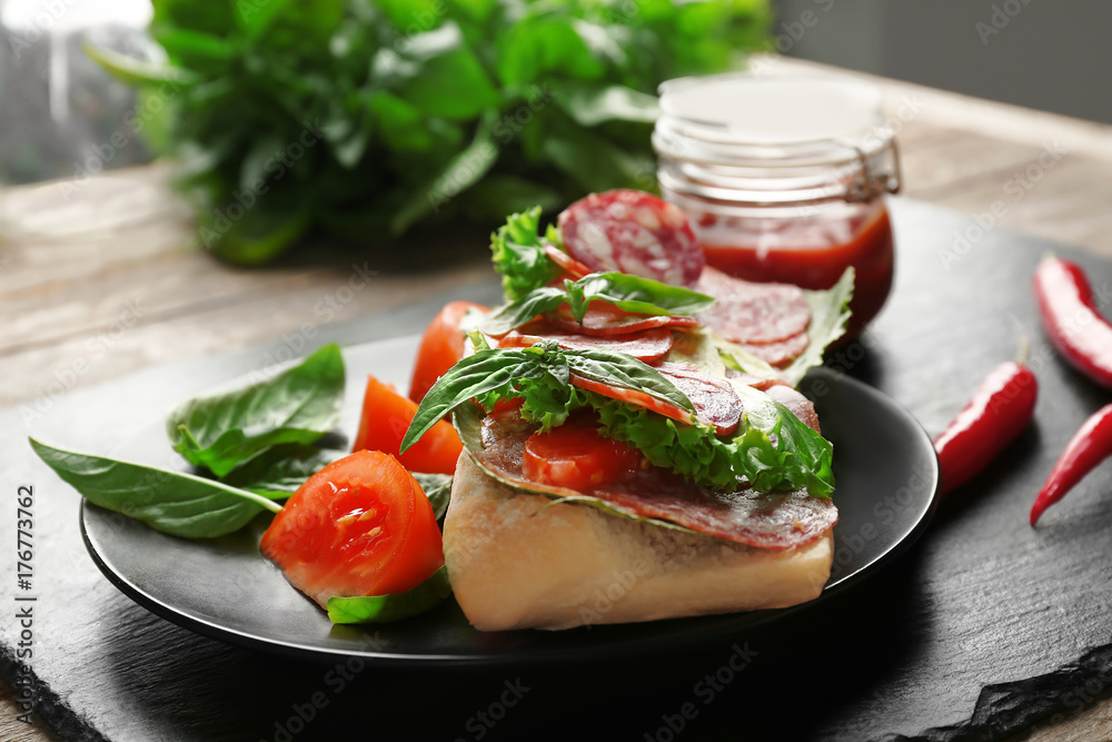 Plate with delicious sausage sandwich on table