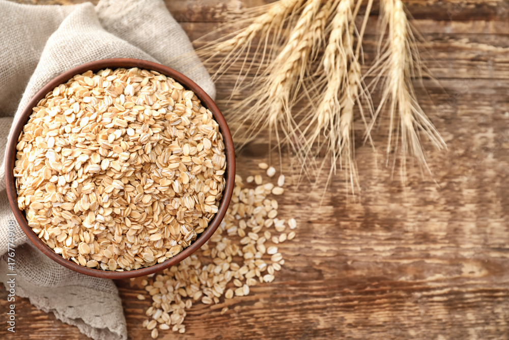 Bowl with oatmeal flakes on wooden background