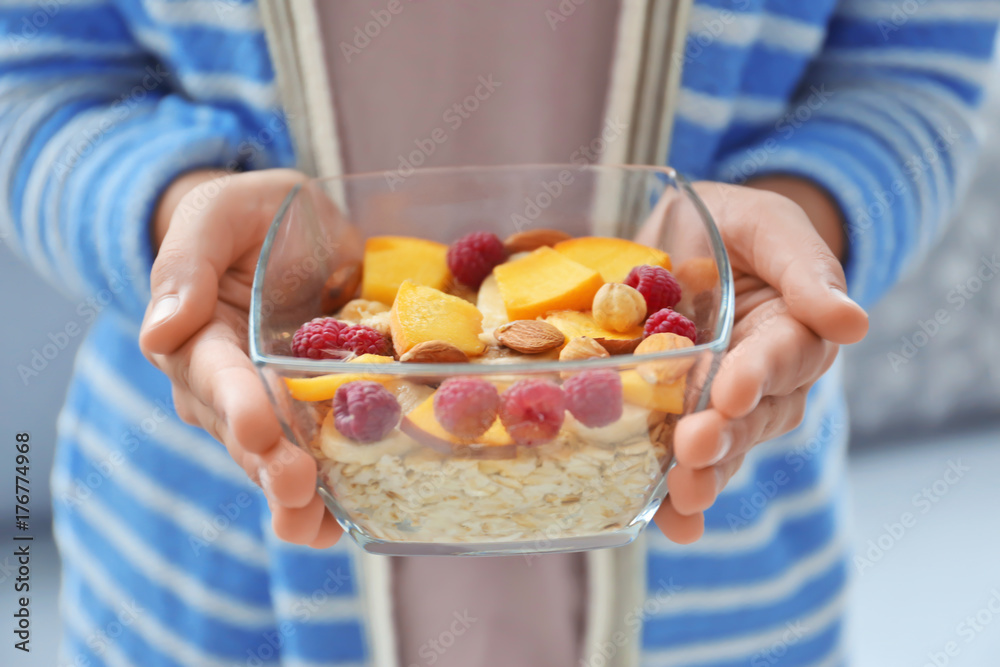 Woman holding bowl with oatmeal indoors