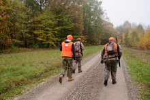 Three Hunters Walking A Dirt Road In The Fall Woods