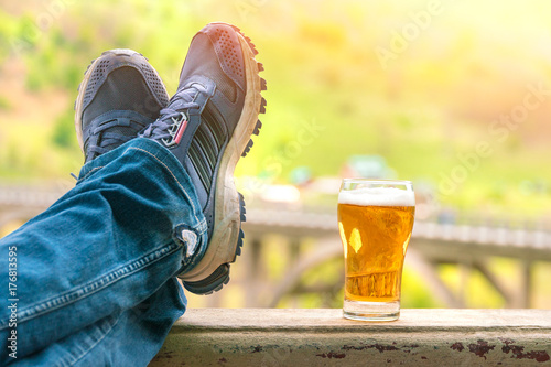 Plakat Nogi w dżinsach i trampkach przy kuflu piwa