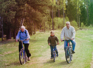 active seniors with grandson riding bikes in nature