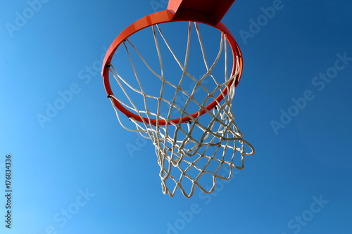 Plakat Pomarańczowy obręczy koszykówki i biały netto przeciw błękitne niebo widziane z dołu