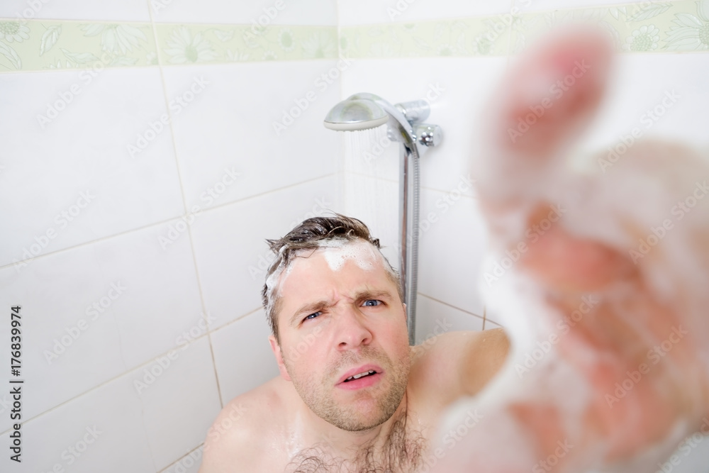 Zdjęcie bez tantiem: A young caucasian man takes a shower and notices a hidden camera. Adobe Stock