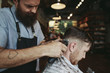 © Rob and Julia Campbell/Stocksy - Stylish modern barber using clippers while giving man a classic haircut