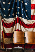 Large Vintage American Flag With An Axe And Old Wooden Seats.