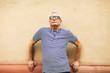 © BONNINSTUDIO/Stocksy - Portrait of an elderly man standing in front a wall.
