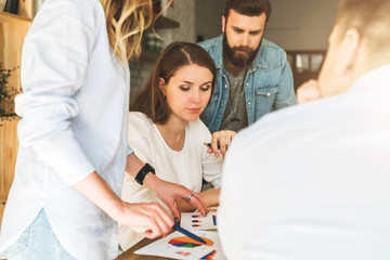 Wall Mural - Group of young businesspeople work together. Brainstorming, teamwork, startup, business planning. Students hipsters learning online. People are discussing business plan. Online education, e-learning.