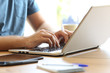 © Antonioguillem - Man hands typing on a laptop keyboard on a desk