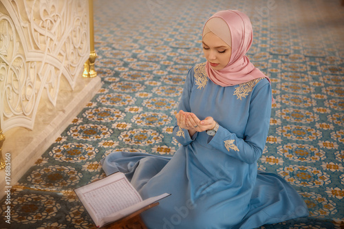 Plakat kobieta, modląc się w meczecie i czytając Koran