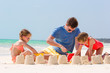© travnikovstudio - Father and kids making sand castle at tropical beach