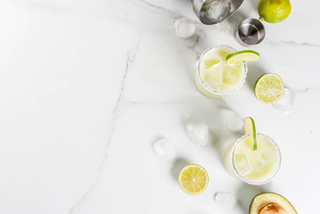 Wall Mural - Alcoholic cocktail recipes and ideas. Avocado and lime margarita with salt, on a white marble kitchen table. Copy space top view