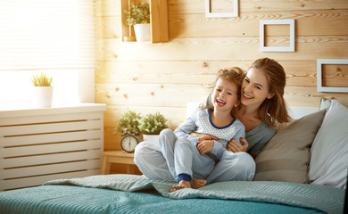 happy family mother and child daughter laughing in bed