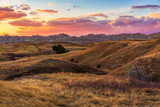 Fototapeta Na ścianę - The sun sets over the golden fields of Badlands National Park, South Dakota