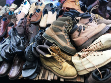 Pile Of Second Hand Shoes On Shelf At Weekend Market.