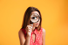 Close Up Of Young Serious Brunette Woman Looking Through Magnifying Glass