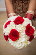 Bride holding bouquet of red roses and white hydrangeas. 