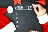 Fototapeta  - Mrs. Santa’s hands writing a wish list on chalkboard