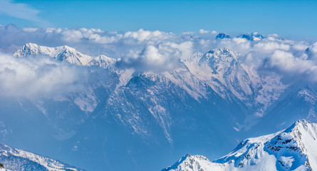 Wall Mural - Alpine landscape with peaks covered by snow and clouds