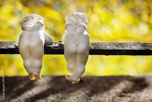 Foto Funny ceramic angels are back view in autumn park.