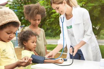 Volunteer doctor measuring blood pressure of poor African child outdoors