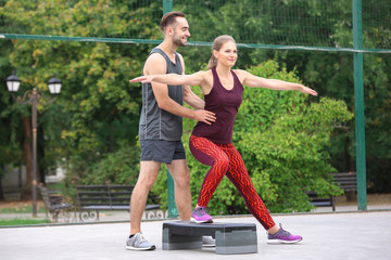 Sticker - Young woman exercising with personal trainer on sports ground