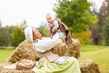 Peasant Mother With Little Baby In Summer Playing On Haystack In The Field