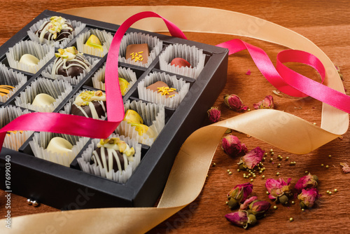 Zdjęcie XXL cukierki ręcznie w pudełko na brązowym tle. ozdobiony wstążkami i kwiatami