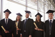 © Monkey Business - Five graduates in mortars and gowns holding certificates